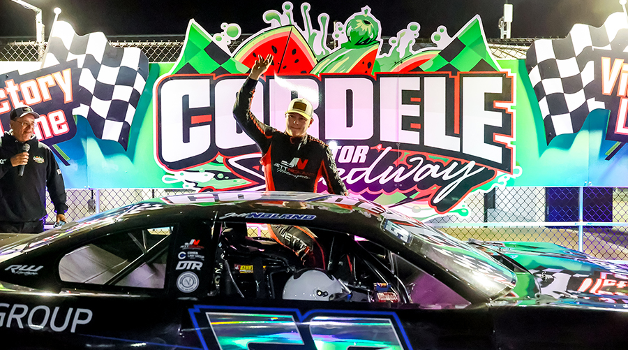 Jett Noland Motorsports celebrates in victory lane at Cordele Motor Speedway. The driver of the #50 car proudly waves to the crowd after a successful race, with the vibrant victory lane backdrop highlighting the celebration at Cordele Motor Speedway.